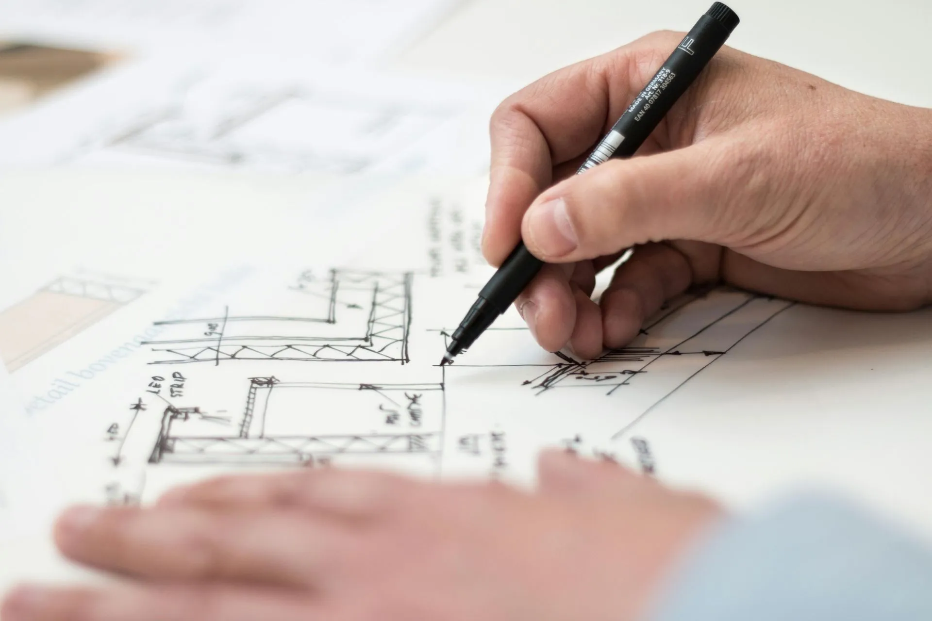 Architect sketching technical drawings with layered documentation